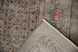 A folded corner reveals the hand-knotted back and distressed floral pile of an Oushak carpet.