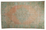 Vintage Distressed Oushak rug, central floral medallion in abrashed peach and pale sea foam green.