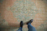 Distressed Oushak carpet with soft peach and seafoam green palette, showing areas of low pile.