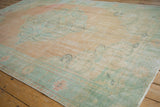 Distressed texture of vintage Oushak rug, faded peach, ivory, and sea foam green.