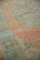 Distressed Oushak carpet with peach field, visible wear, and sea foam green patterned border.