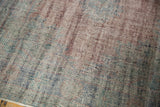 Textured pile of distressed vintage Oushak rug, showing muted blues and faded brick red.