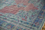 Distressed vintage Oushak carpet segment, displaying faded raspberry, pale blue, and seafoam motifs.