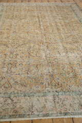 Distressed texture of the Sparta carpet, showing faded scrolling vinery in dusty gold and mauve.
