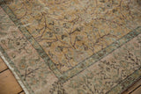 Distressed Sparta rug corner: worn dusty gold, pale mauve, and green floral tendrils.