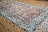 Distressed vintage Sparta carpet corner details scrolling vinery with apricot, terracotta, and ivory floral arabesque motifs.