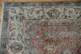 Corner of vintage Sparta rug showing distressed floral vinery, apricot, ivory, and blue colors.