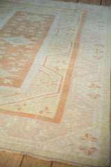 Distressed wide border and pinwheel florals on vintage Oushak rug in pale orange, ivory.