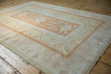 Distressed Oushak rug section with faded orange medallion, germinating buds, and pinwheel floral motifs.