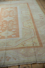 Distressed Oushak rug border with pale burnt orange and ivory pinwheel floral motifs.