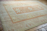 Muted texture and even wear on a vintage Oushak rug, with pale burnt orange and ivory floral motifs.