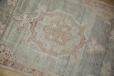 Distressed silver and pale terracotta meandering vine border on a vintage Oushak rug.