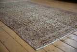 Distressed Sparta carpet corner, with worn ivory and brown vinery revealing faint foundation.