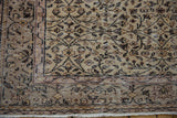 Distressed Sparta carpet corner showing even pile wear, scrolling vinery, and fringe.