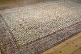 Distressed vintage Sparta carpet's textured field, revealing ivory and bronze scrolling vinery with worn details.