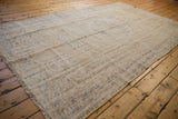 Distressed Oushak rug pile showing wear, soft ivory and pale royal blue floral patterns.