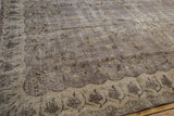 Close-up of distressed Sparta carpet's scalloped border, showing floral motifs and worn texture.