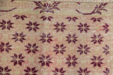 Textured close-up of distressed Sparta rug showing faded ivory, rose, and red floral starbursts.