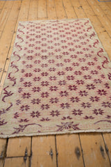 Sparta rug detail: distressed black cherry floral starbursts, faint foundation, vine border.