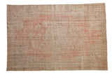 Distressed Oushak carpet displaying pale rose and ivory faded floral motifs with textured wear, 5'8