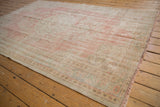 Distressed pile and intact selvage of a vintage Oushak rug in pale rose, ivory, and seafoam green.
