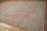 Distressed Oushak carpet side with fringe, revealing pale rose, ivory, and seafoam green.
