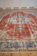 Worn cherry red, sky blue, and ivory arabesque motifs on a distressed Sivas carpet.