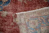 Distressed cherry red pile revealing foundation, with woven back and fringe of Sivas rug.