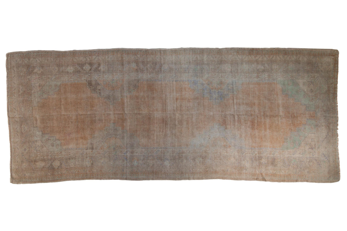 Vintage distressed Oushak rug runner with a large, faded medallion in pale sandalwood, silver, and slate.