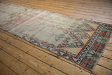 Distressed vintage Oushak runner's panel motif with brick, mint, saffron geometric plants.