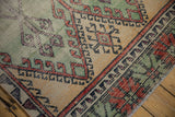 Geometric design transition of the distressed vintage Oushak runner in mint green, pale saffron, and brick.