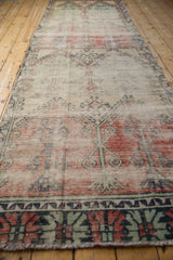 Textured distressed Oushak runner features geometric panels in brick, mint, and visible foundation wear.