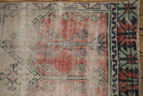 Distressed Oushak rug detail: brick, mint, charcoal geometric plants, exposed foundation, and fringe.