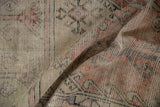 Folded detail of the distressed Oushak runner, showing worn geometric patterns in brick, mint, and silver tones.