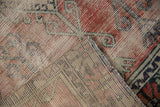 Close-up of folded distressed Oushak rug runner, showing worn brick pile with geometric plants and linear reverse.