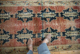 Distressed brick red abrashed field, navy cloudband medallions, with wear and foundation showing.