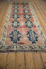 Distressed Sparta runner: navy cloudband medallions on abrashed brick red field, visible wear.