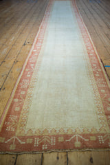 Secured fringe, terra cotta germinating plant border, and ivory field of a vintage Oushak runner.