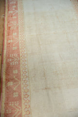 Distressed Oushak runner's soft ivory pile and terra cotta germinating plant border.