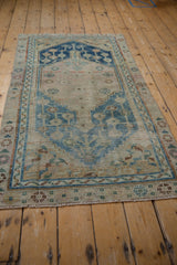 Distressed Anatolian rug corner detail, showing faded indigo blue geometric patterns and wear to knot heads.