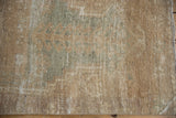 Faded seafoam green and ivory patterns on distressed Oushak rug pile, showing wear, secured selvage.