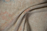 Textured fold of the distressed Oushak rug, revealing its soft pile and muted ivory-pink hues.