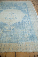 Soft, even wear on a distressed vintage Oushak carpet shown from a low angled perspective.