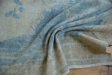 Soft, flexible weave of a distressed Oushak showing worn knot heads in blue and beige.