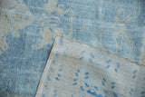The hand-knotted reverse and low-pile texture of a vintage distressed Oushak carpet corner.