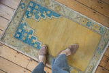 Worn gold pile and sky blue border of a distressed vintage Oushak rug.