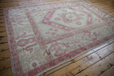 Distressed Oushak rug corner showing wide aubergine cloudband border and worn texture.