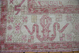 Distressed vintage Oushak carpet: wide main border with pale aubergine cloudband motifs and visible wear.