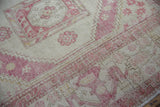 Distressed Turkish Oushak rug's pale aubergine pinwheel florals with even wear on ivory.