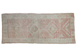 Distressed vintage Oushak runner, repeating dusty raspberry, ivory, and beige geometric medallions, 4'1